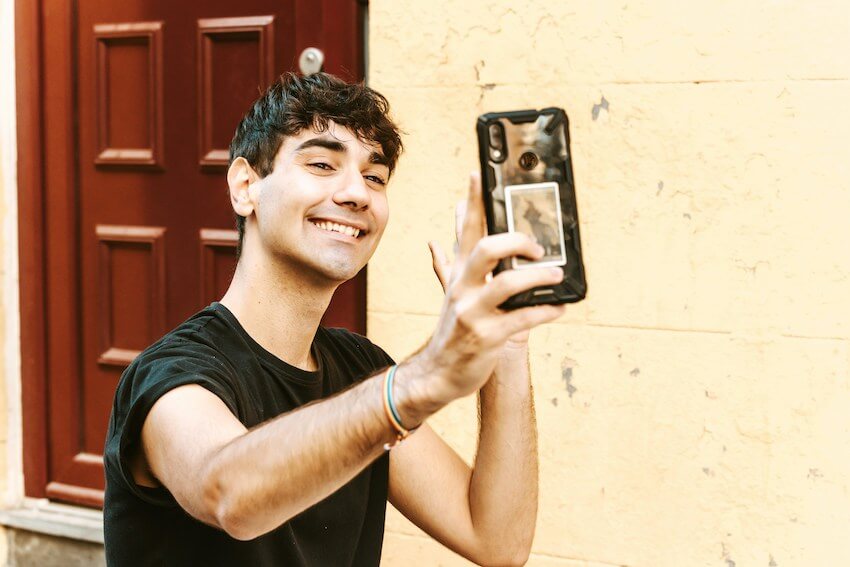 smiling man waving to his friend on video chat