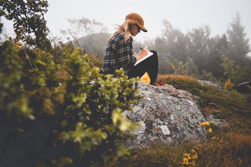 woman sitting on a rock journaling